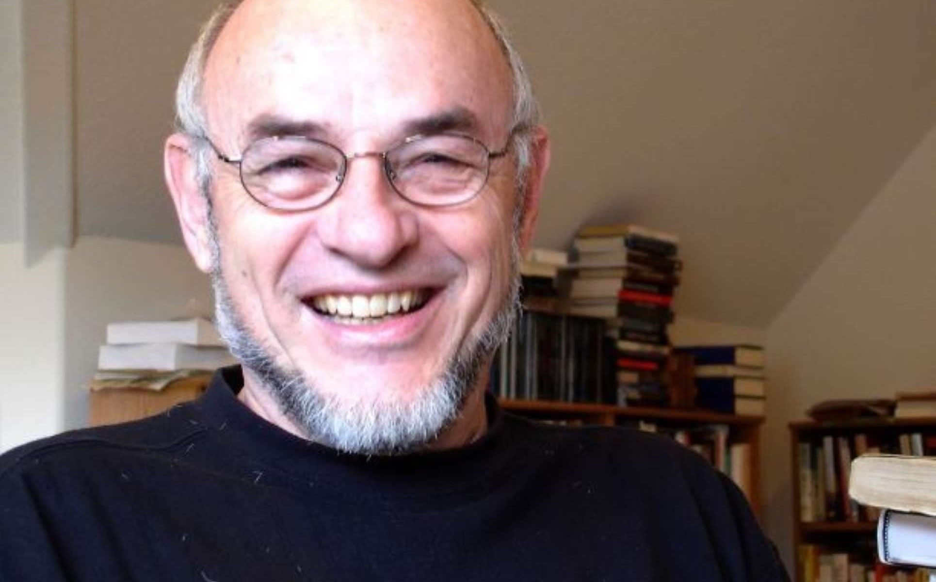A headshot of author Richard Etulain smiling while wearing wire-rimmed glasses and a black mock neck