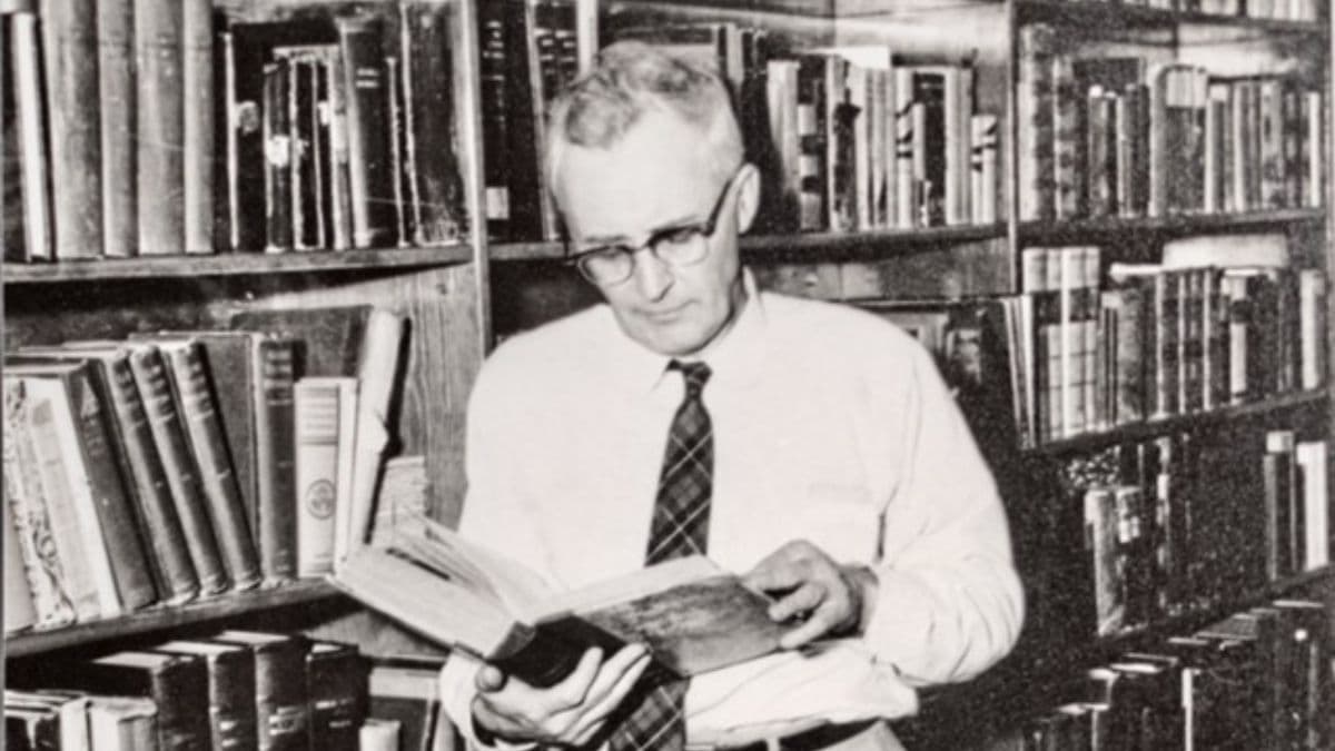 Hugh Nibley holding a book with many footnotes.