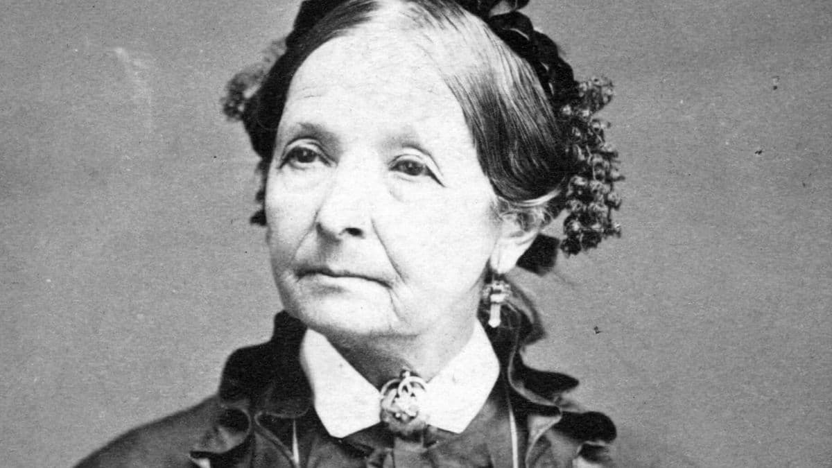A soulful 1875 portrait of Eliza R. Snow, Latter-day Saint poet and leader. Her steady, weathered gaze and firm expression capture the resilience she preached in her discourses on overcoming trials. She is wearing a dark ruffled dress with a white collar and an ornate brooch.